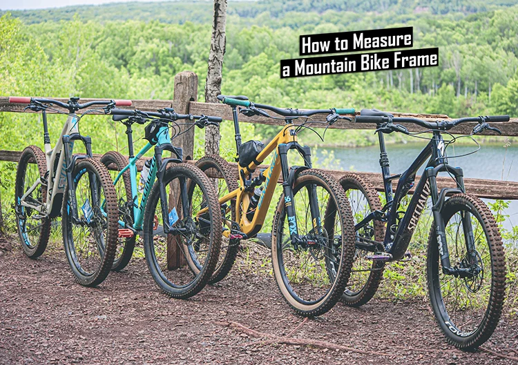 four mountain bike frames leaned against a wooden fence