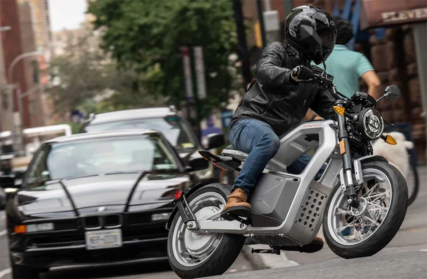 man riding a sondors metacycle electric motorbike on city streets, wearing full gear