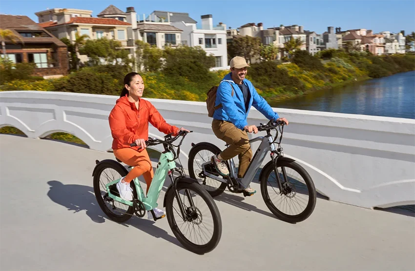 man and woman riding velotric electric bikes across a bridge